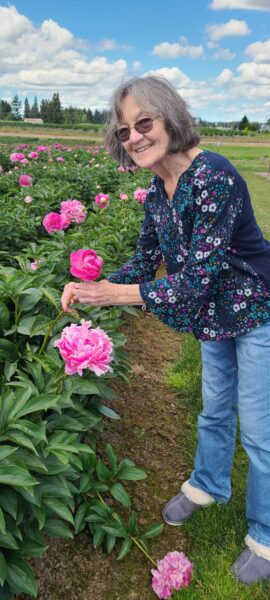 elderly woman smelling flowers in a field